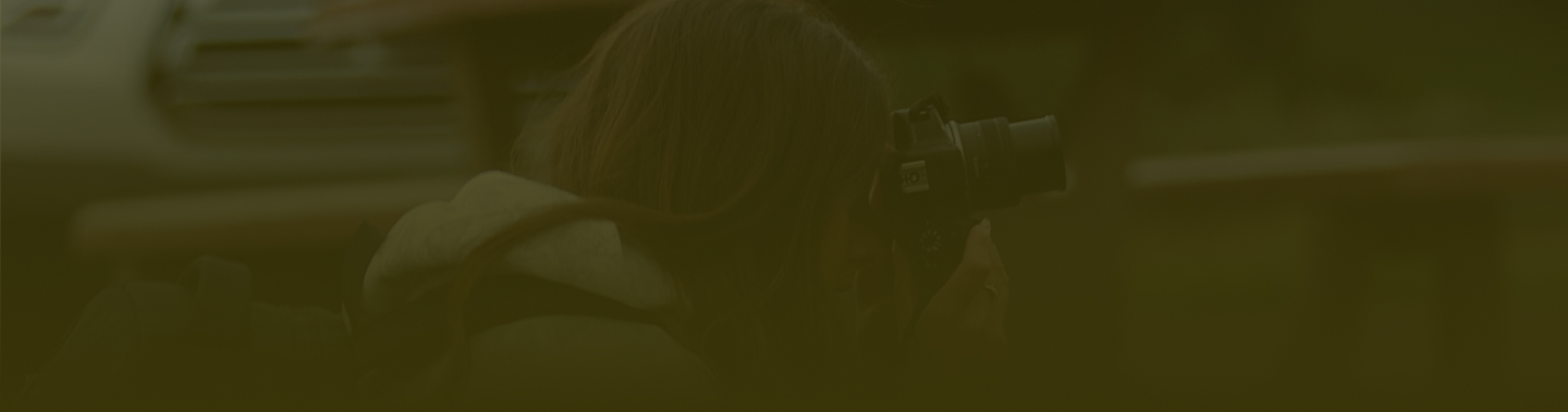 woman kneeling with camera taking photos with a dark green overlay