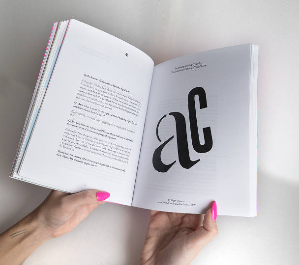 Book being held open to display a page layout design from the Designer Interviews project